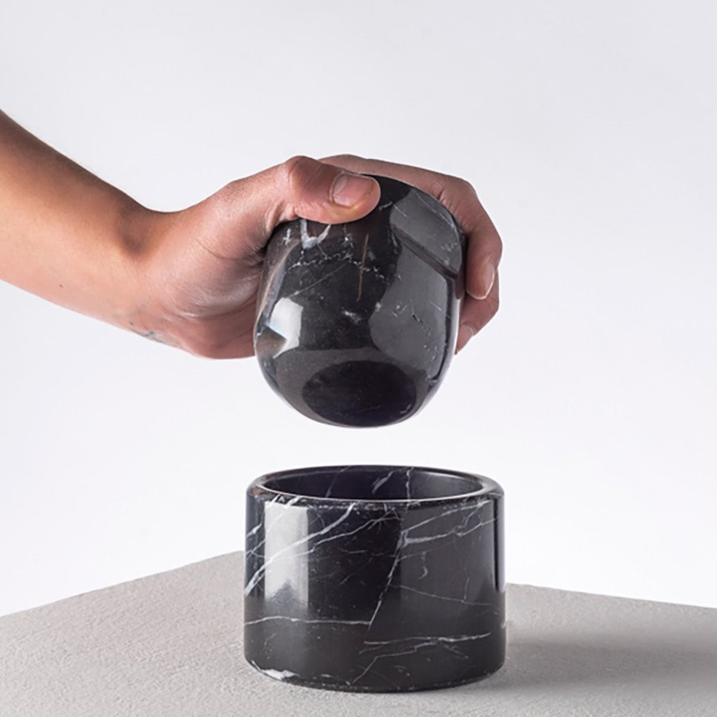 Hand holding a black marble modern nut cracker on a light gray background