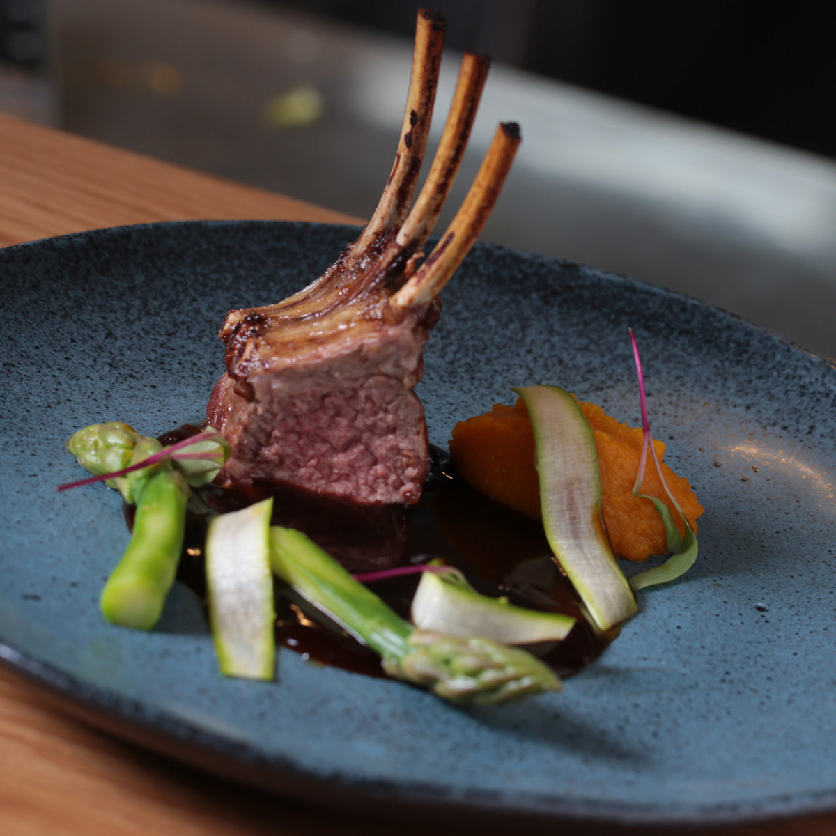 Lamb dish with asparagus and carrots on a blue plate