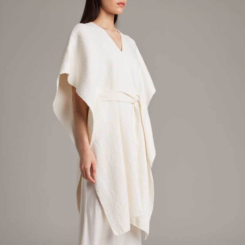 White dress with a draped design on a plain background
