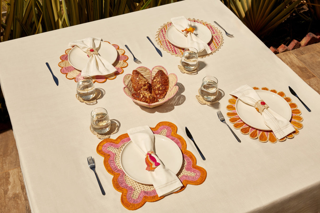 Dining table set with plates, glasses, and cutlery on a white tablecloth.