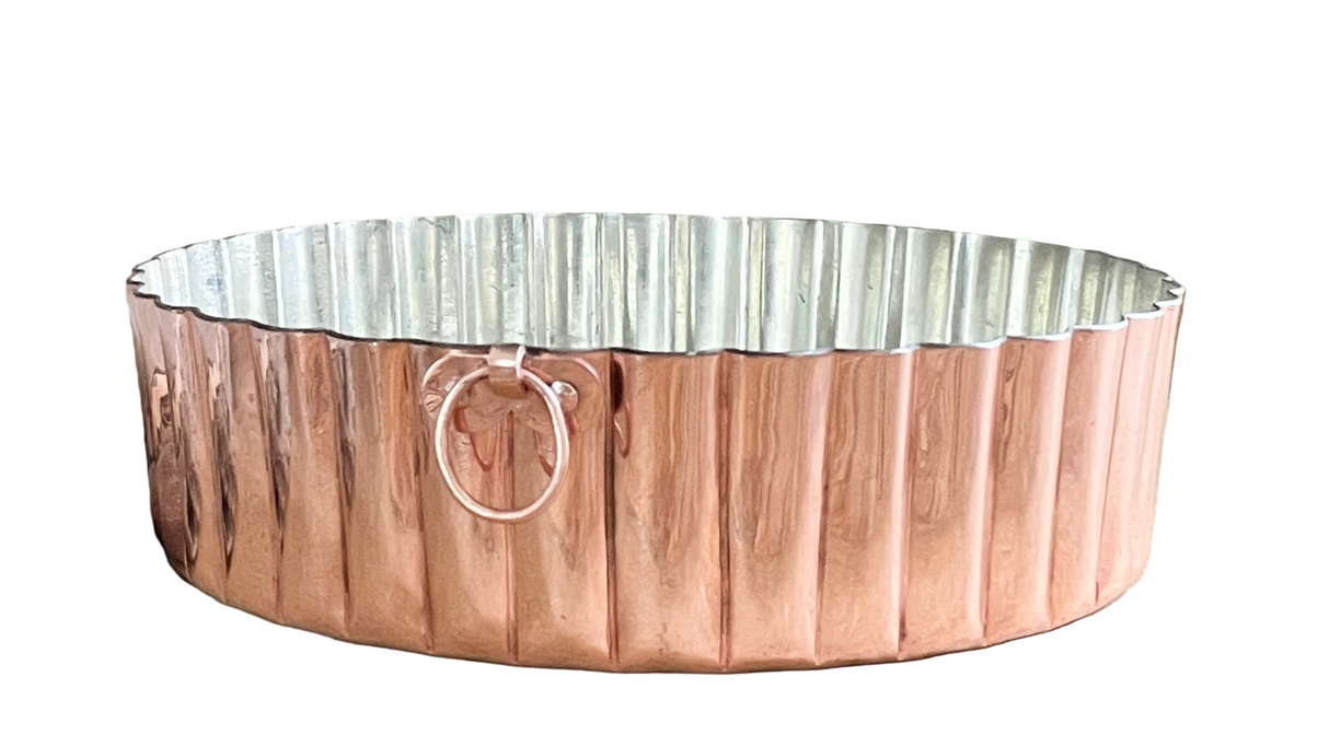 Copper scalloped cake pan on a white background