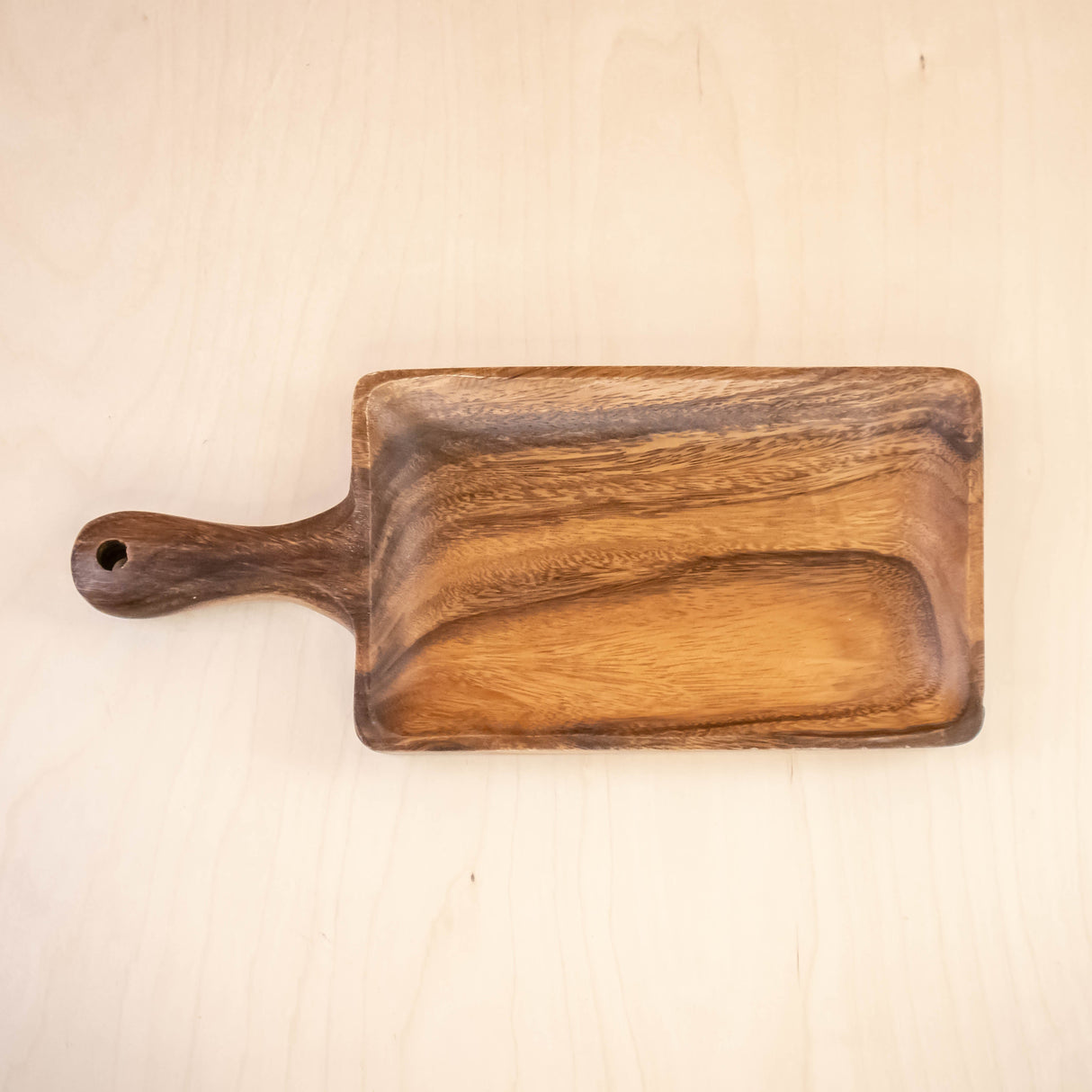 Wooden cutting board with a handle on a beige background