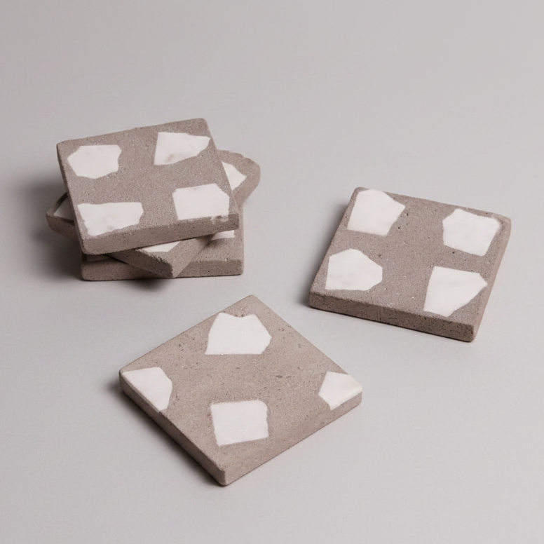 Three square coasters with white heart patterns on a light gray background