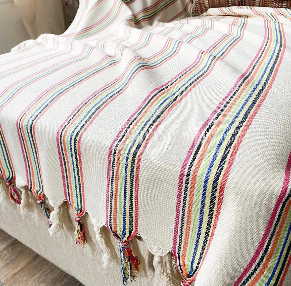 Striped blanket with colorful stripes and tassels on a white background