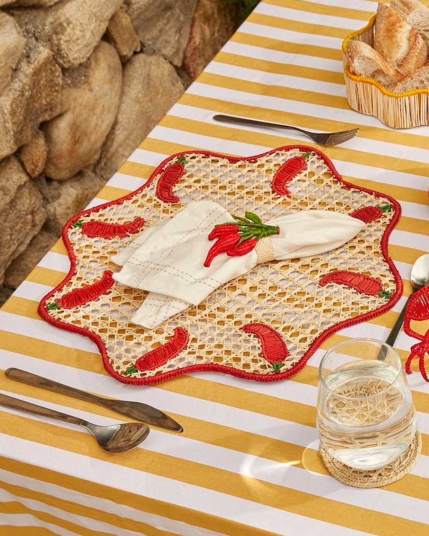 Outdoor setting with a striped tablecloth, plates, cutlery, and snacks on a stone wall background.