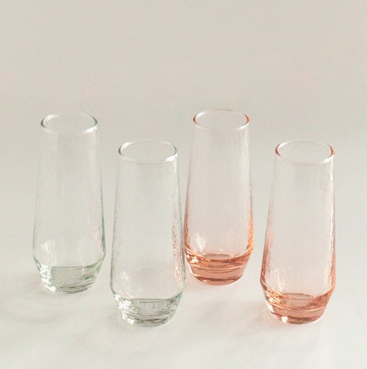 Four glass tumblers with pink bases on a light gray background