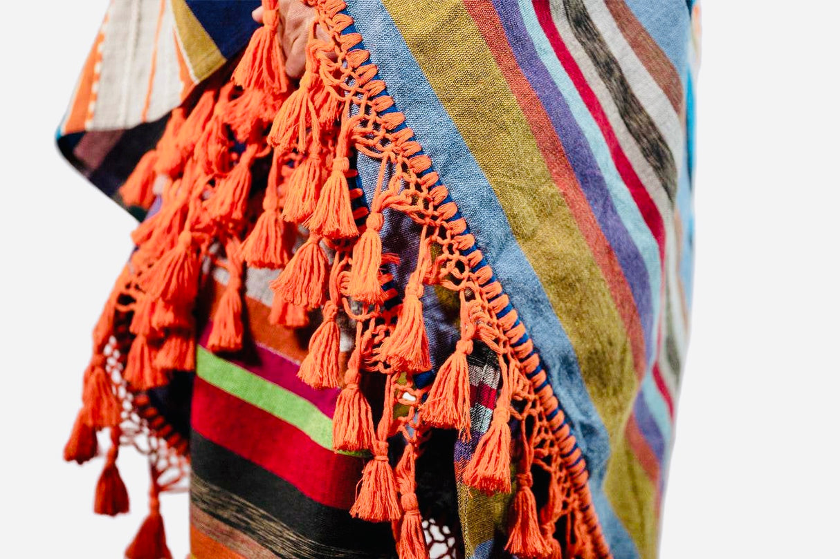 Colorful striped fabric with orange tassels on a white background