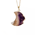 Crescent moon-shaped amethyst pendant on a gold chain against a white background
