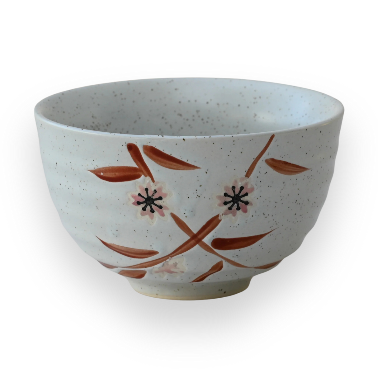 The Bamboo Matcha Bowl is a speckled white ceramic bowl featuring a painted floral design on a black background, showcasing the elegance of Minoyaki pottery, and is perfect for a traditional matcha tea ceremony.