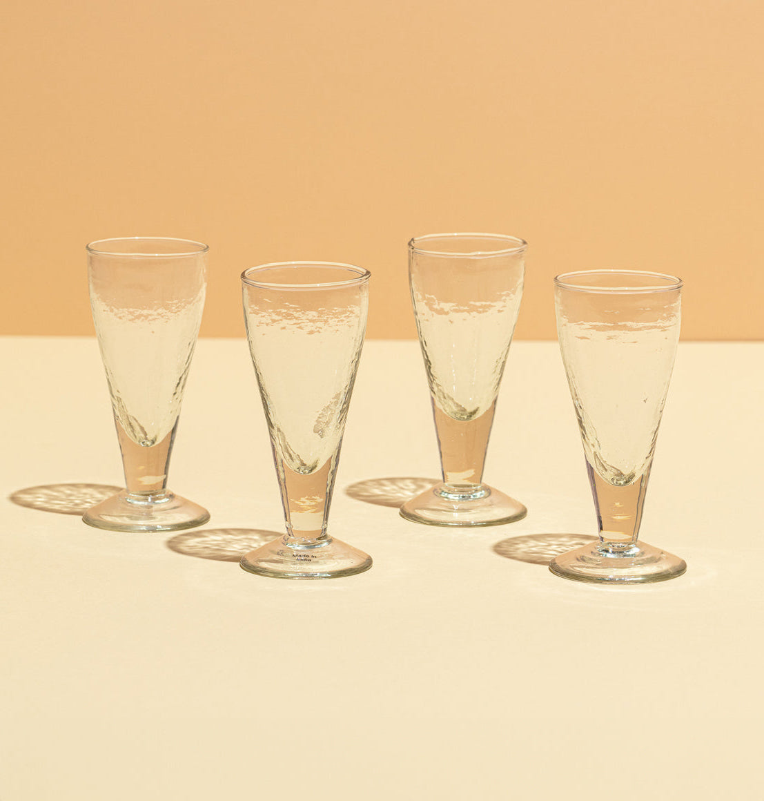 Four champagne flutes with a beige background