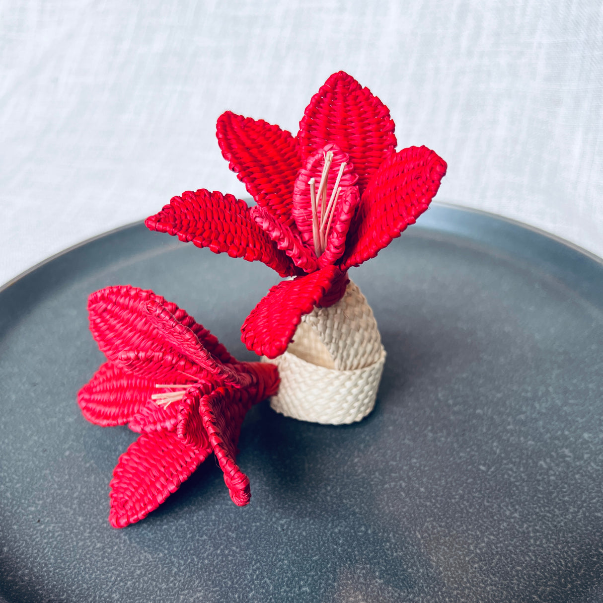 Red knitted flower napkin rings on a gray plate with a white background