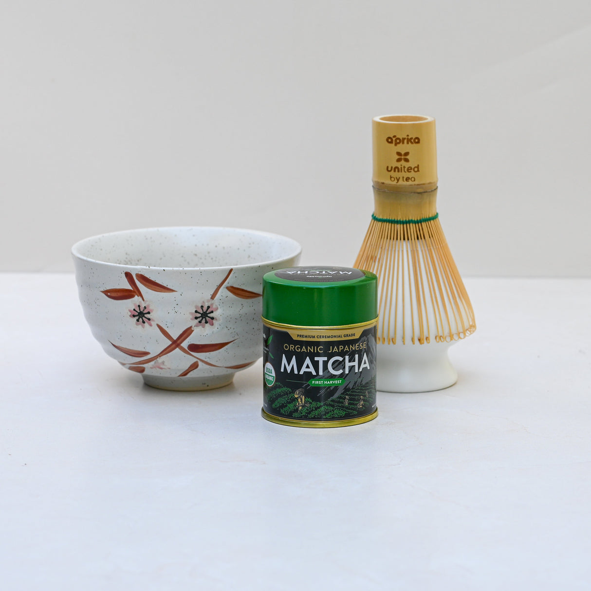 The Bamboo Matcha Bowl and Bamboo Matcha Whisk with Holder Set rest elegantly on a white surface, embodying the essence of a perfect matcha tea set.