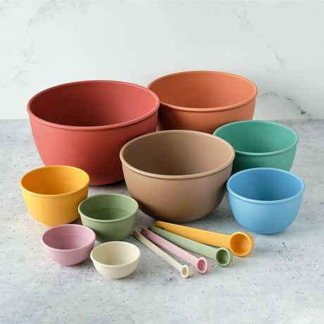 Set of colorful bowls and measuring cups on a light gray surface