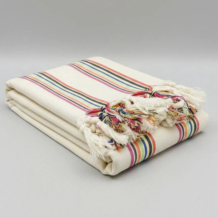 Beige blanket with colorful striped pattern and tassels on a white background