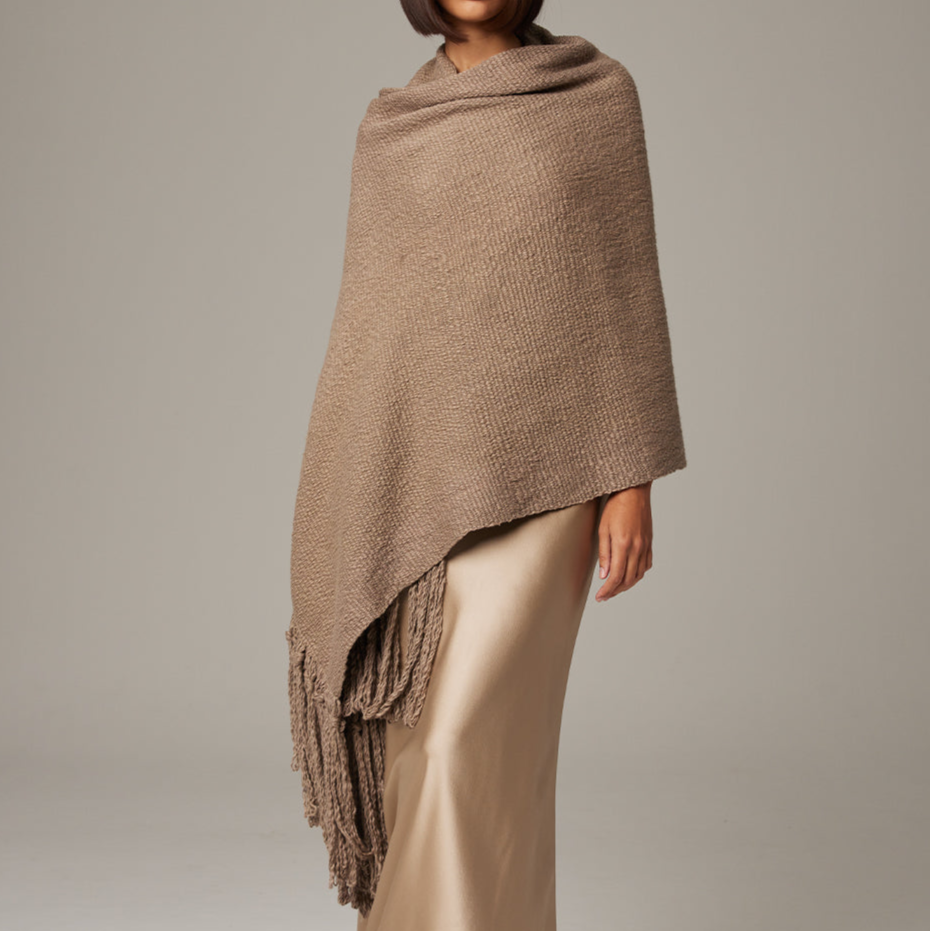 Brown knitted shawl draped over a person on a plain background
