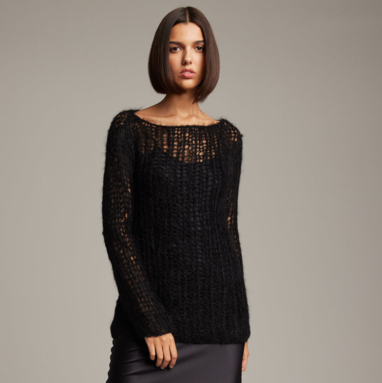 Woman wearing a black textured sweater against a gray background