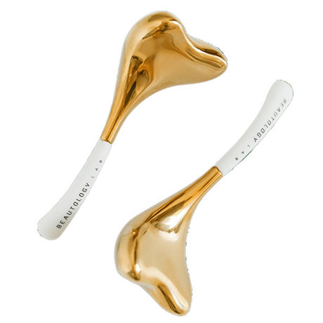 Two gold-colored skincare tools with white handles on a white background