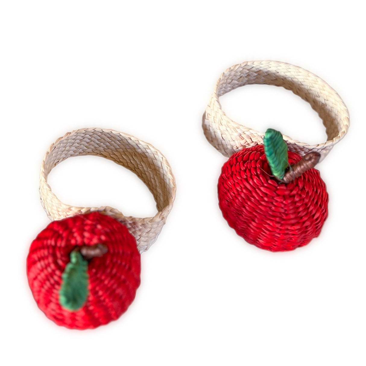 Two red apple-shaped napkin rings with woven bases on a white background