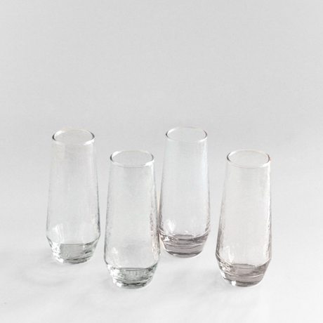 Set of four clear glass tumblers on a light gray background