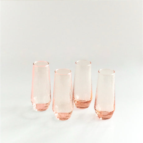 Set of four pink glass tumblers on a light gray background