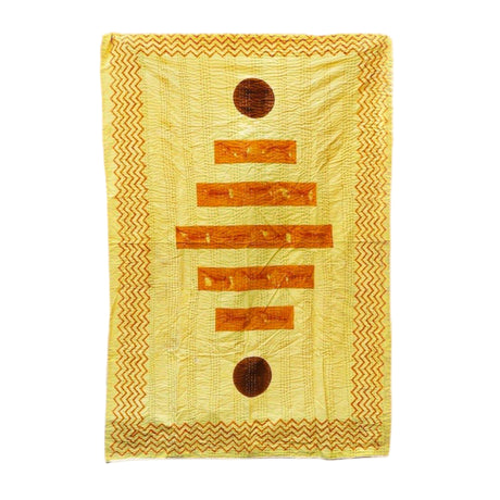 Yellow quilt with brown circular patterns on a white background
