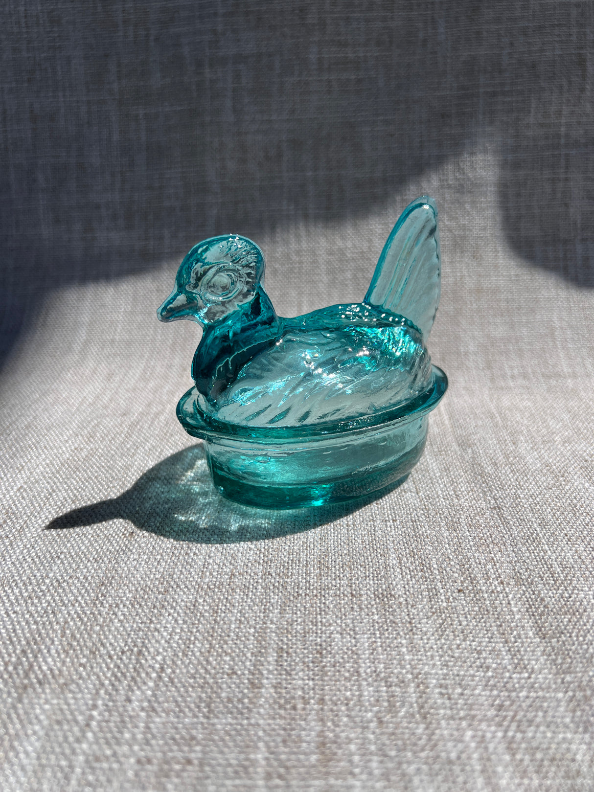 Blue glass bowl with a lid on a textured surface