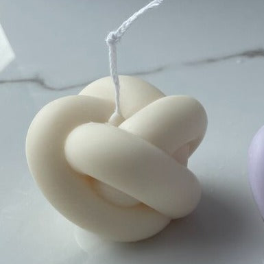 White knot-shaped candle on a white background