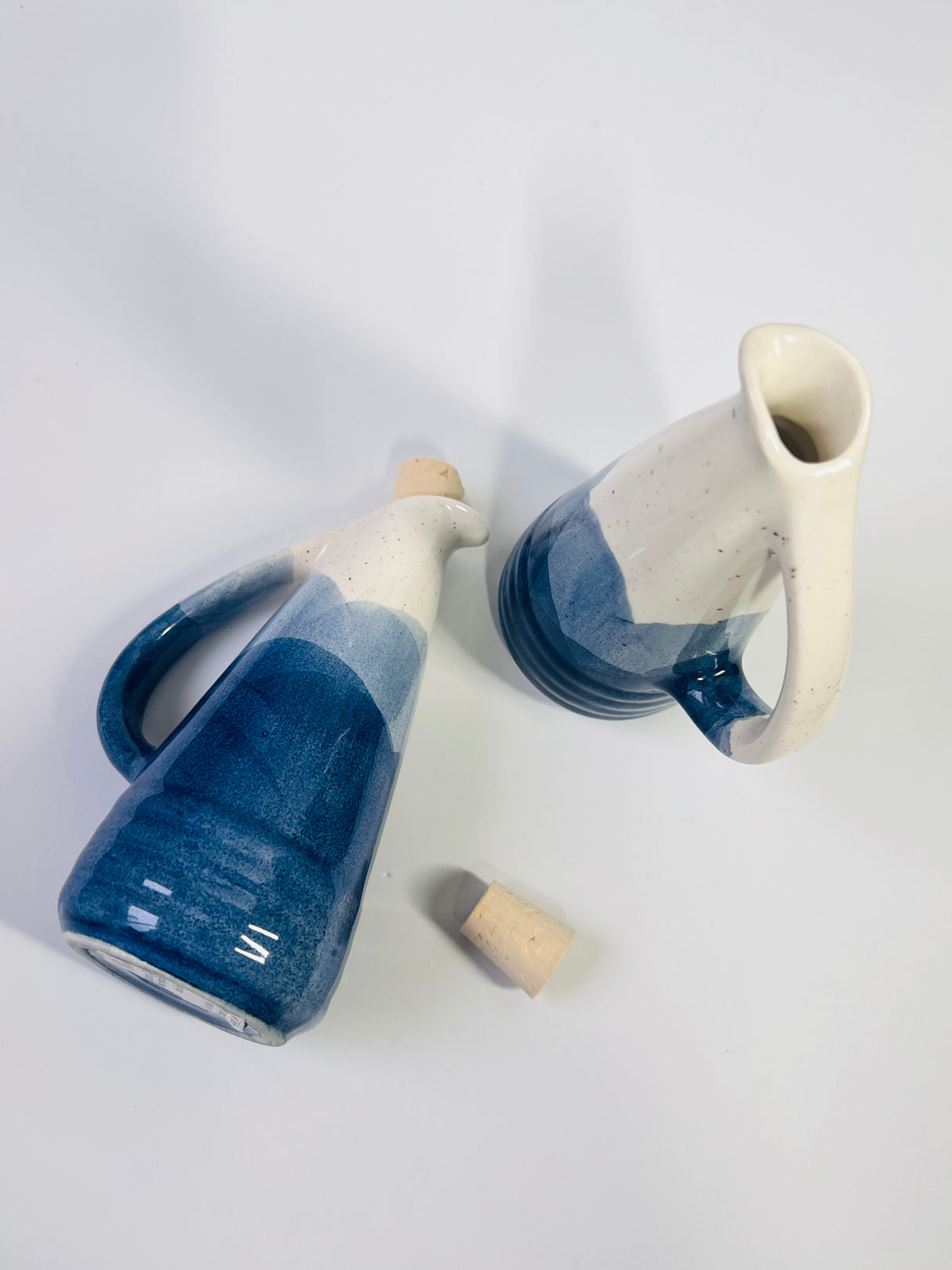 Two ceramic pitchers with blue and white gradient on a light gray background