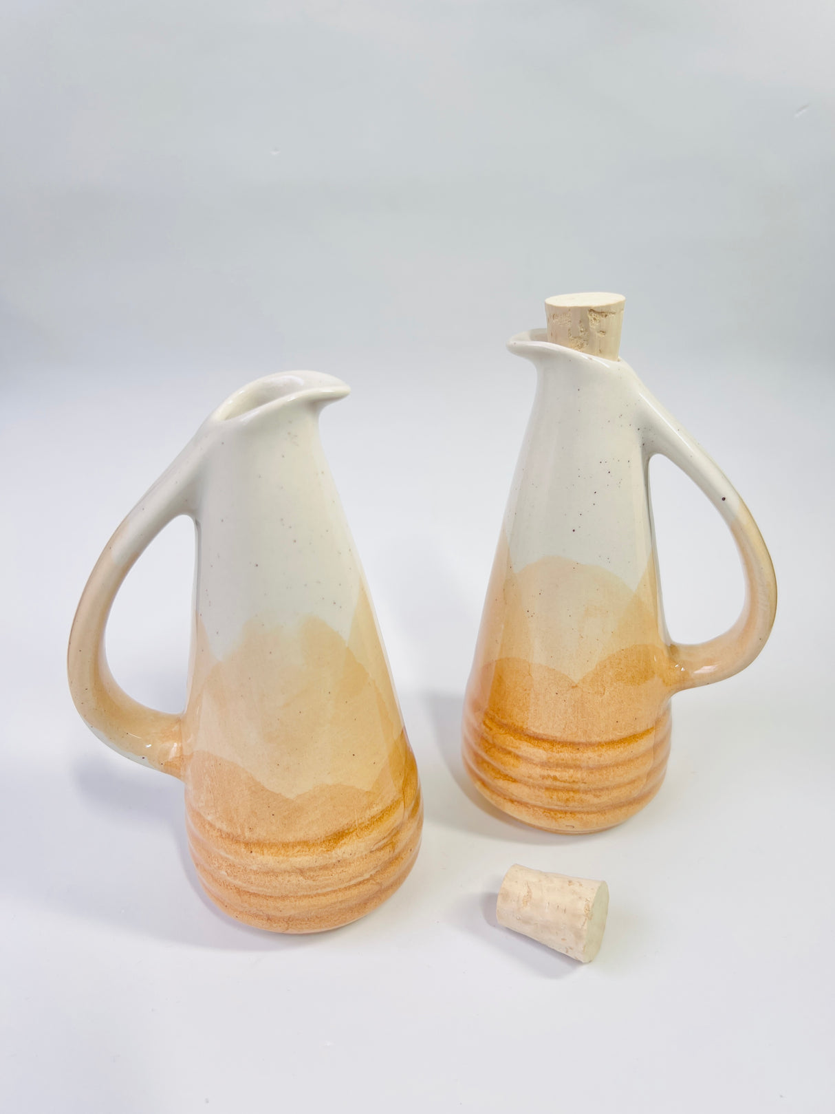 Two ceramic oil bottles with gradient design on a light gray background