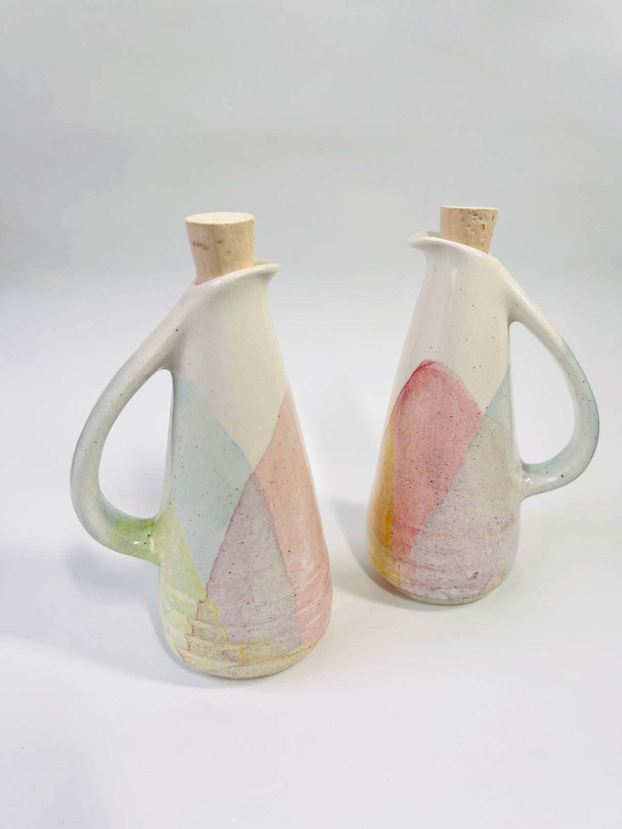 Two ceramic pitchers with abstract designs on a white background
