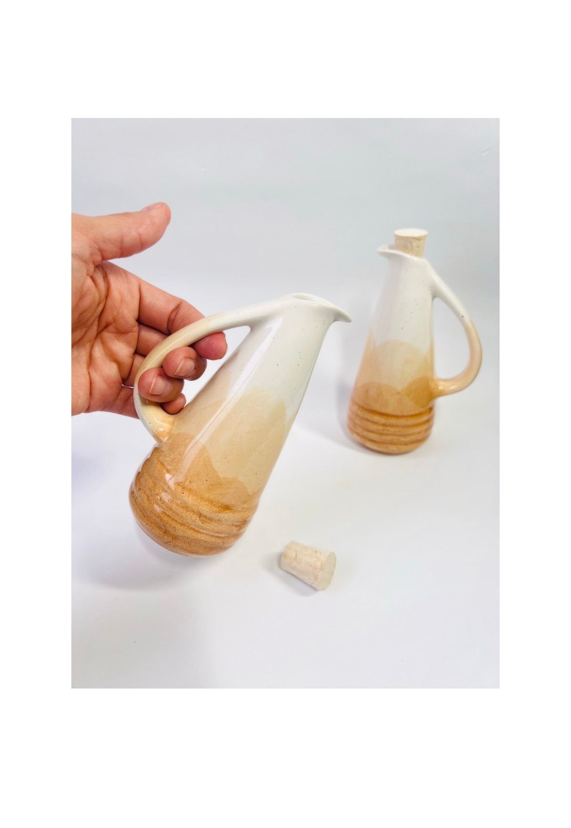 Hand holding a ceramic pitcher with a gradient design on a white background