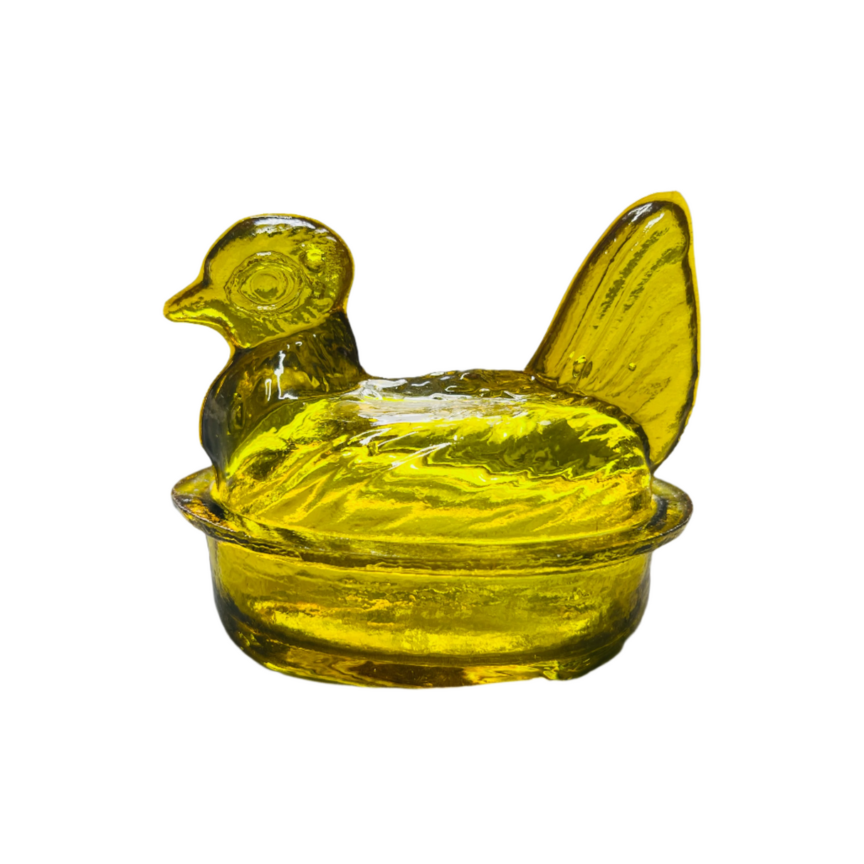 A hand blown glass nesting hen bowl & lid in a honey yellow color, with a translucent appearance.