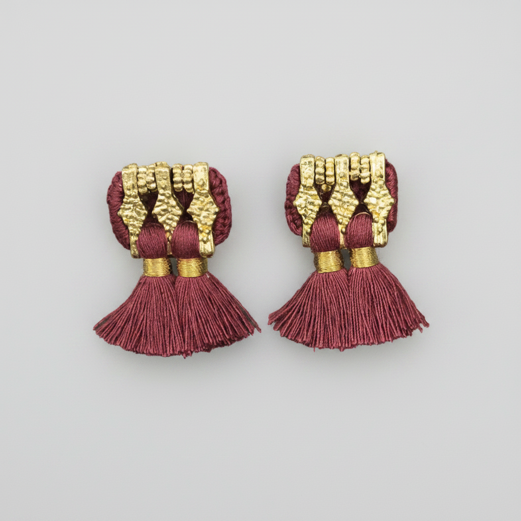Pair of red and gold tassel earrings on a white background