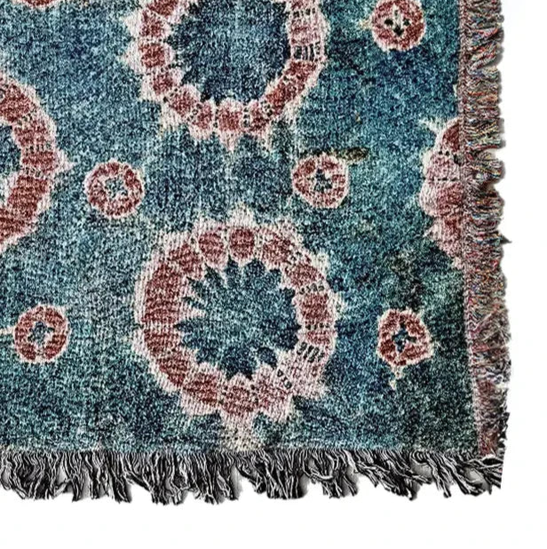 Decorative blanket with circular patterns and fringed edges on a white background