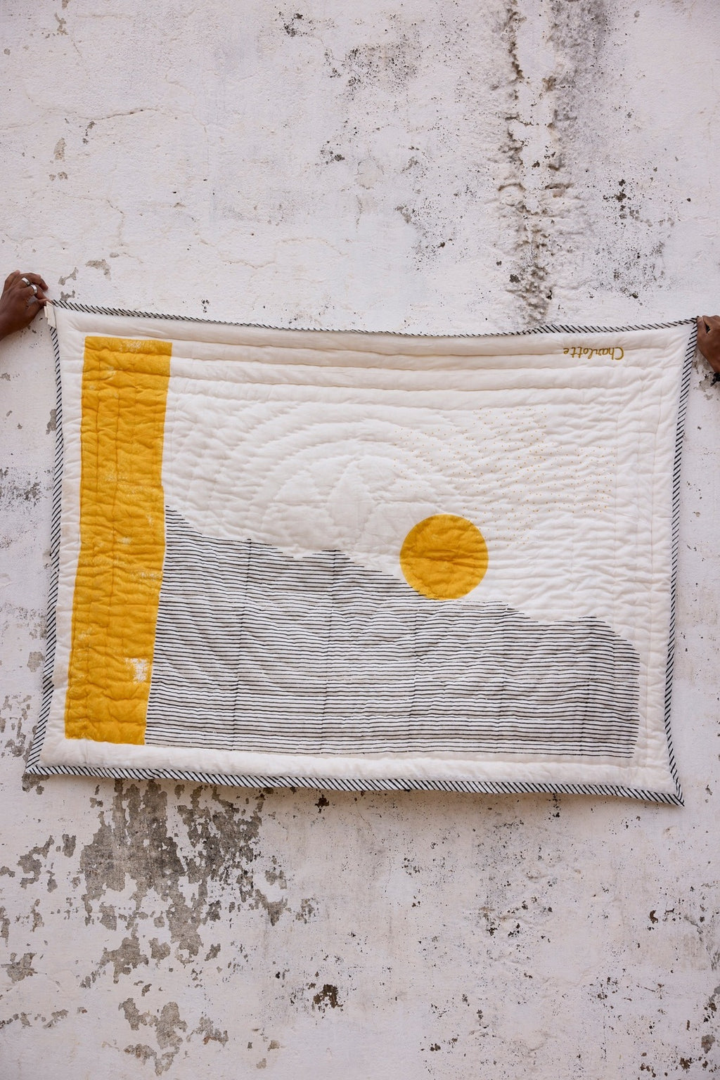 Textile art piece with a yellow square and circular design on a textured surface