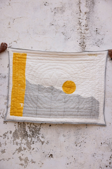 Textile art piece with a yellow square and circular design on a textured surface