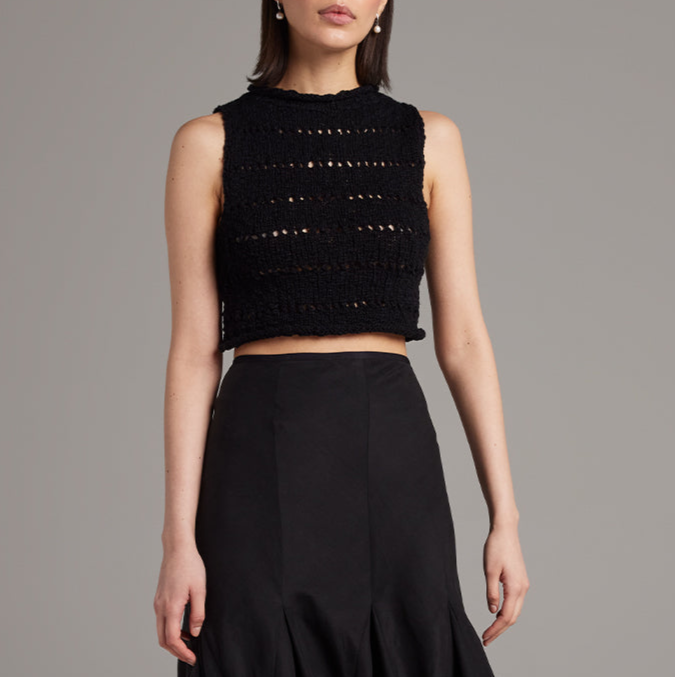 Black sleeveless top with embellishments worn by a model on a gray background