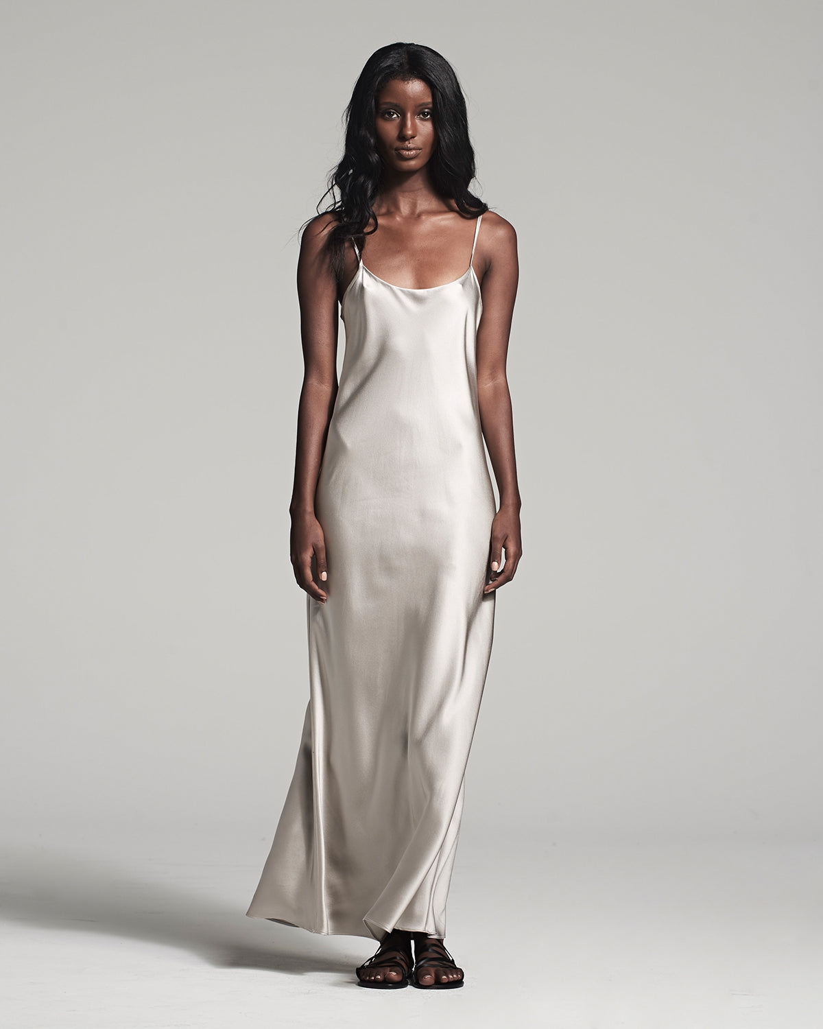 Woman wearing a white satin slip dress against a gray background