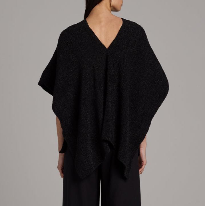 Black poncho worn by a person on a gray background