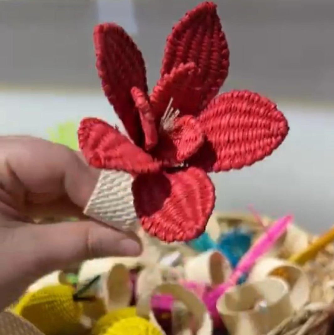 Red flower-shaped napkins ring held by a hand with a blurred background