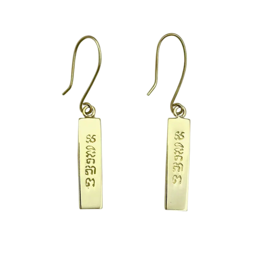 Gold earrings with engraved text on a white background
