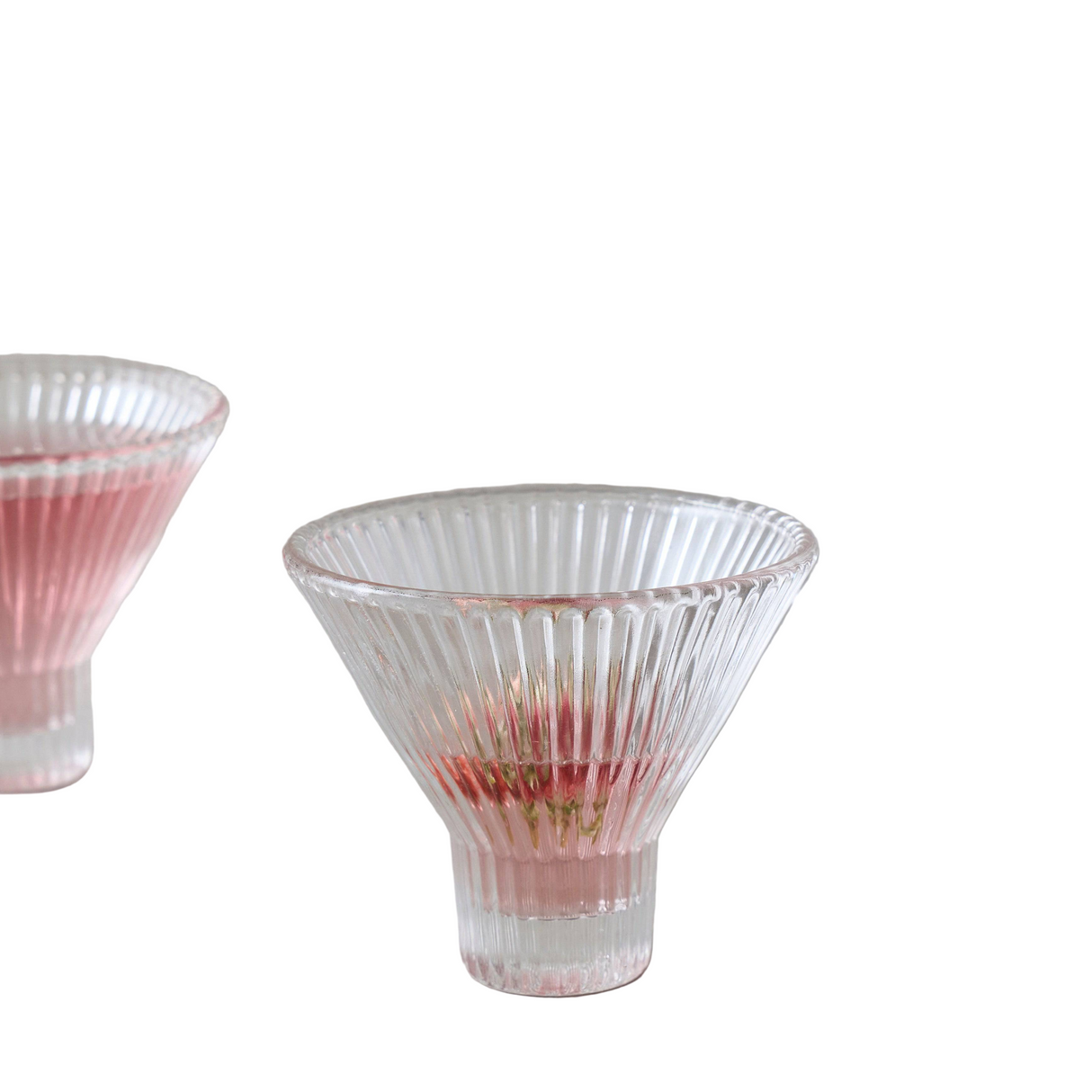 Two ribbed glass tumblers with pink interior on a white background