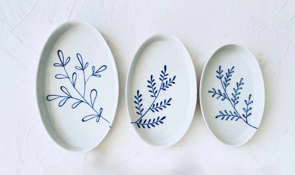 Three oval ceramic plates with blue leaf patterns on a white background. Süheyla Nesting Plates