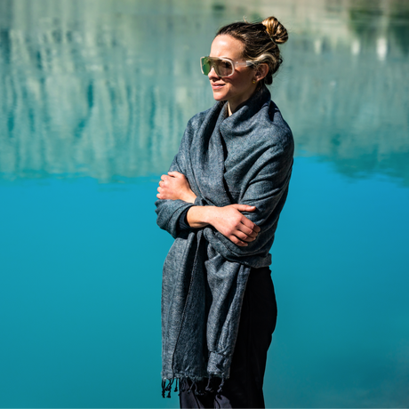 Woman wearing a gray scarf and sunglasses by a pool
