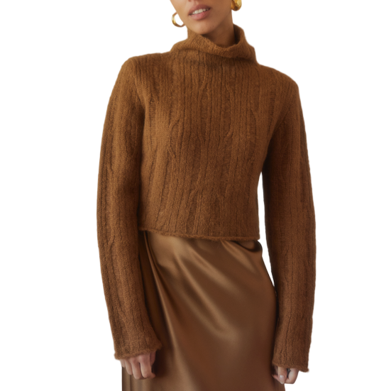 Woman wearing a brown ribbed sweater and satin skirt on a white background
