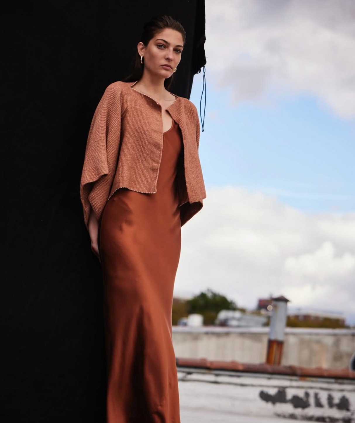 Woman in a brown outfit standing outdoors with a scenic background