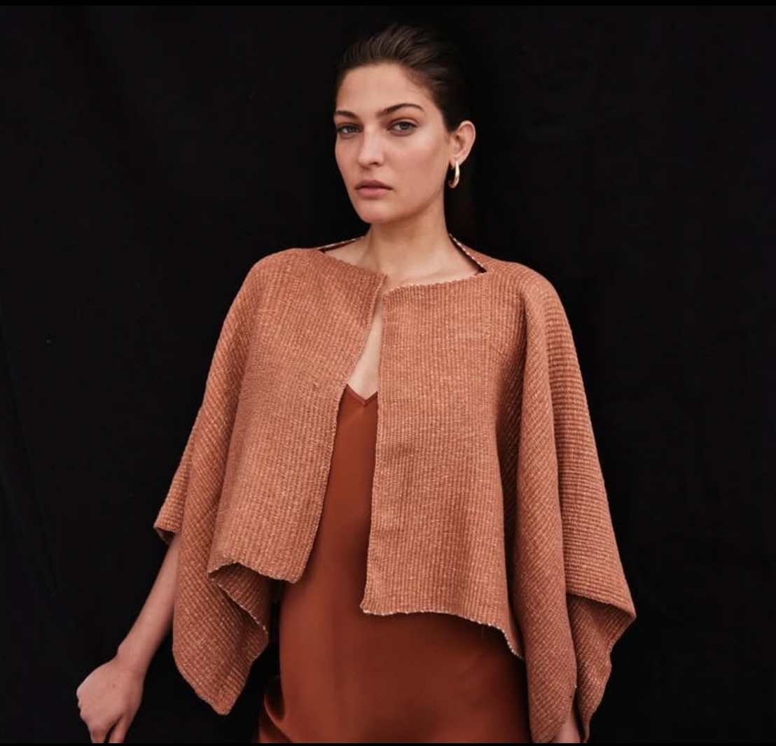 Woman wearing a brown textured shawl against a black background