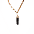Gold chain necklace with a black tassel pendant on a white background