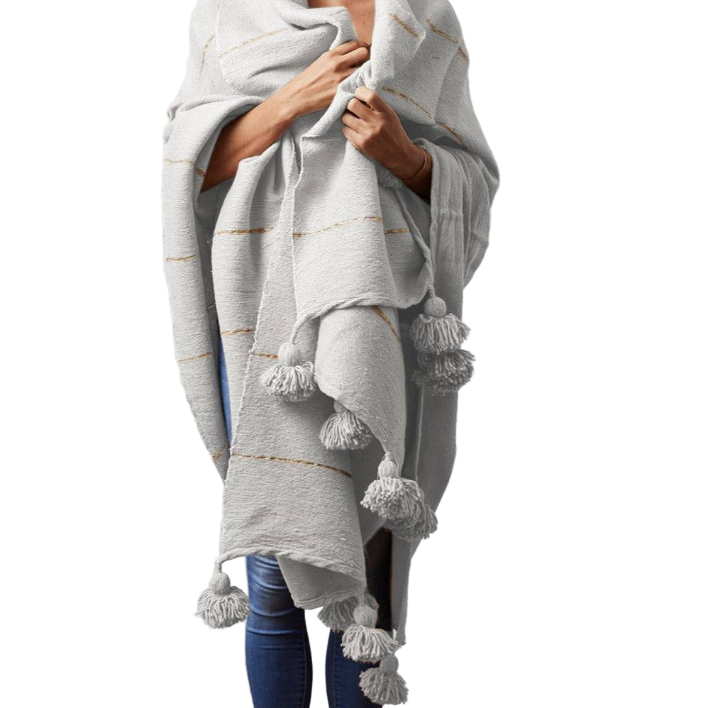Person wearing a gray poncho with tassels on a white background