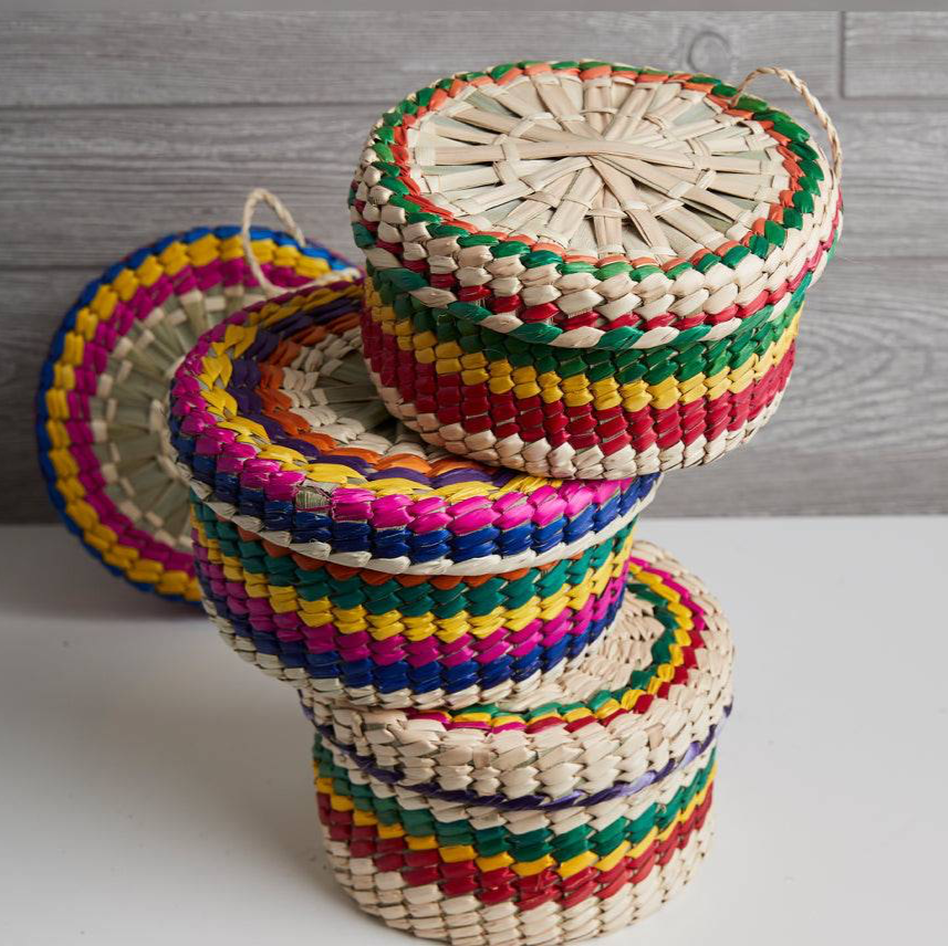 Stack of colorful woven baskets on a light surface with a wooden background